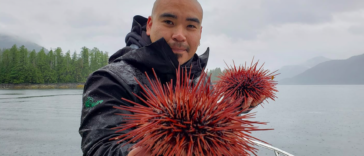 Douglas Neasloss holding two sea urchins.