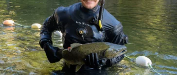 Zach Kapelan briefly holds a chinook salmon before releasing it back into HIŁSYAQƛIS/Tranquil Creek to spawn.