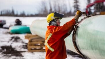 A Trans Mountain pipeline worker on site, next to the constructed pipeline.