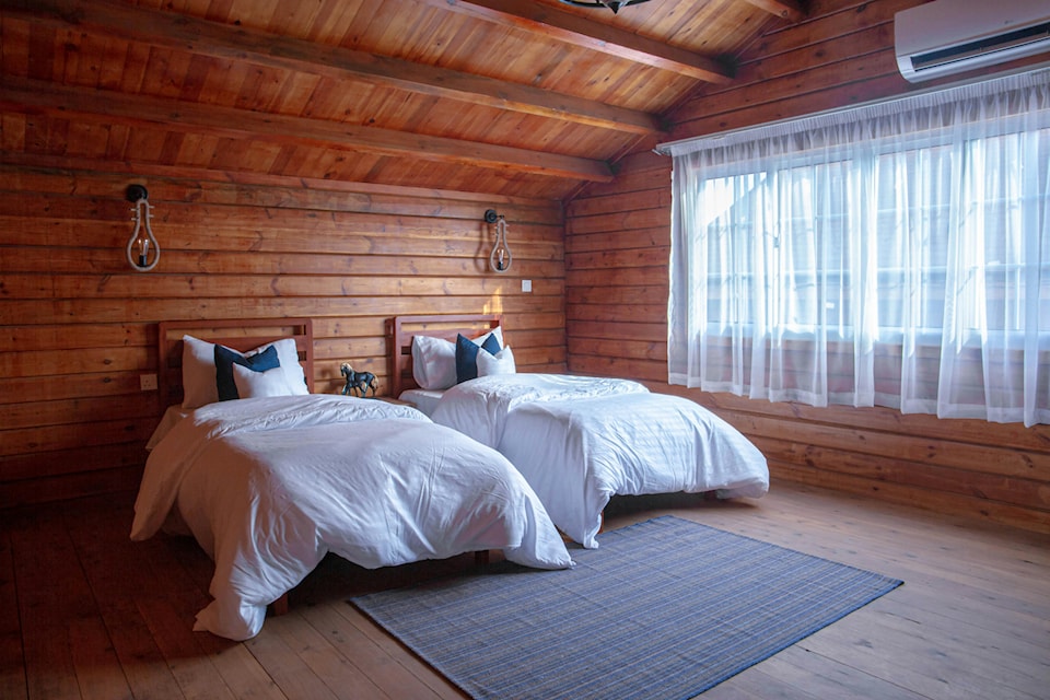 wooden cabin bedroom with two large beds next to a window