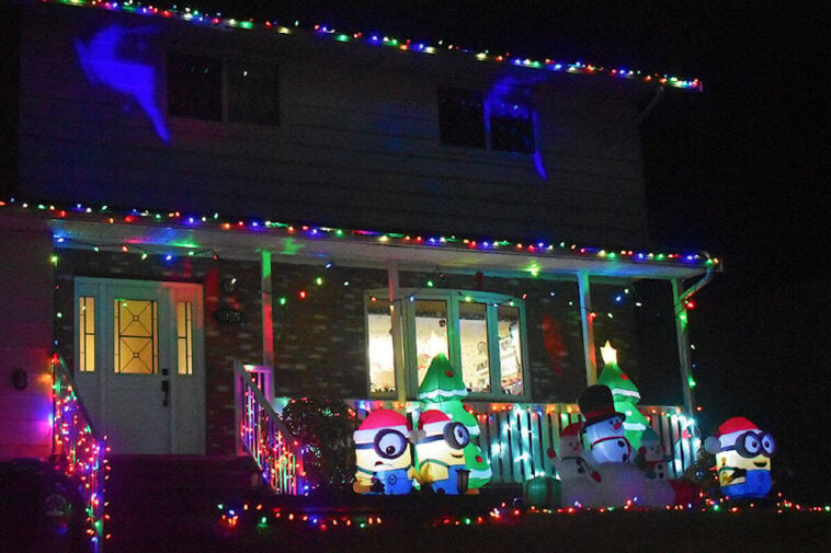 Neighborhood house at night lit up with christmas lights, minion inflatables snowmen and christmas decorations